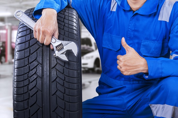 INFINITI tire service technician with wrench and tire